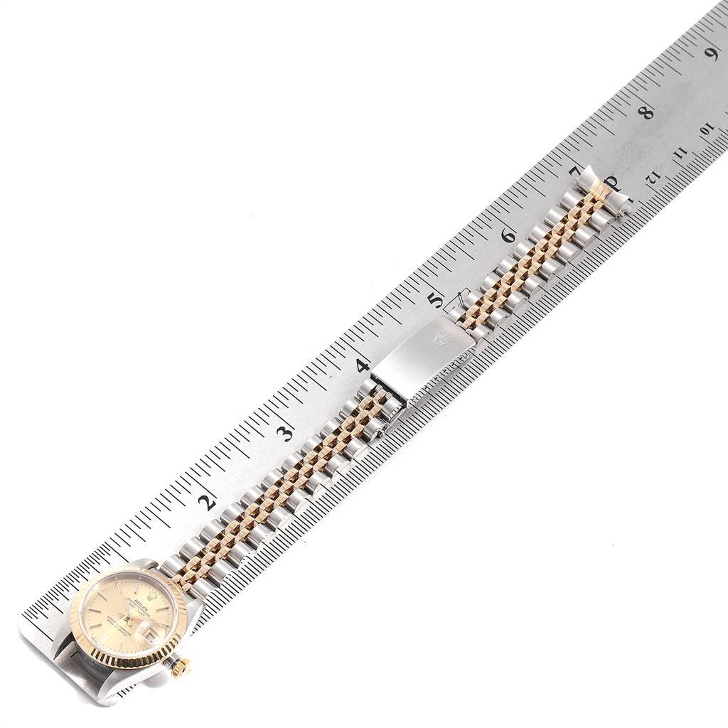 The Rolex Datejust 79173 Women
s Steel and Gold (two tone) Champagne Dial 79173 Women
s Steel and Gold (two tone) Champagne Dial watch is shown horizontally with its gold and silver bracelet and clasp stretched and measured against a ruler.