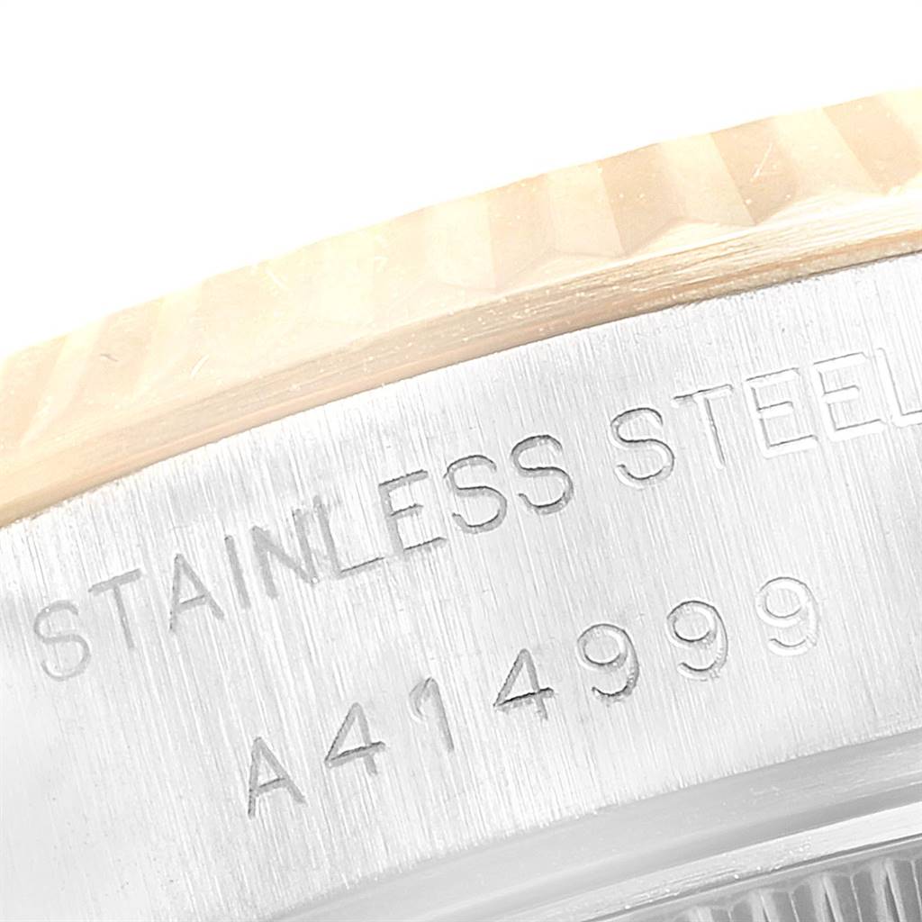 The image shows a close-up angle of the bezel and case side of a Rolex Datejust 79173 Women
s Steel and Gold (two tone) Champagne Dial 79173 Women
s Steel and Gold (two tone) Champagne Dial watch, featuring the serial number and "STAINLESS STEEL" engraving.