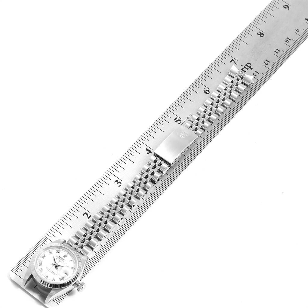 The image shows a Rolex Datejust 79174 Women's Stainless Steel White Dial 79174 Women's Stainless Steel White Dial watch with a metal bracelet laid flat beside a ruler.