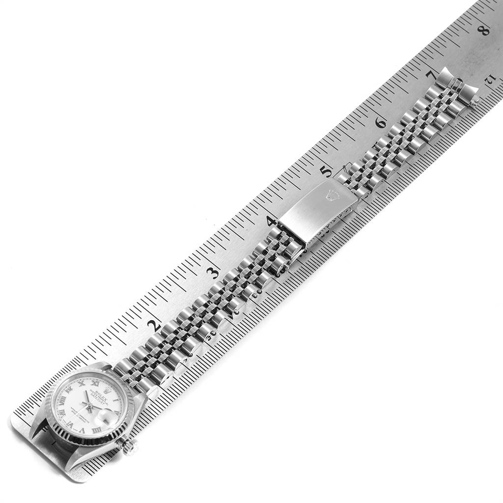 The Rolex Datejust 79174 Women
s Stainless Steel White Dial 79174 Women
s Stainless Steel White Dial watch is shown laid out flat, alongside a ruler, displaying its face and full bracelet.