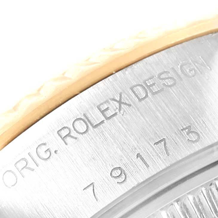 The image shows a close-up of the engraved case back of a Rolex Datejust 79173 Women
s Steel and Gold (two tone) Grey Dial 79173 Women
s Steel and Gold (two tone) Grey Dial watch, displaying partial text and serial numbers.
