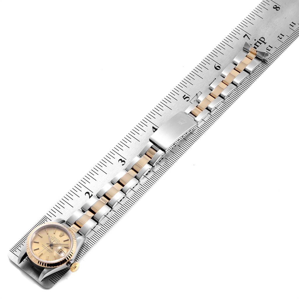 The image shows a Rolex Datejust 69173 Women's Stainless Steel Champagne Dial 69173 Women's Stainless Steel Champagne Dial watch with a gold dial and a stainless steel and gold bracelet, placed alongside a measuring ruler.