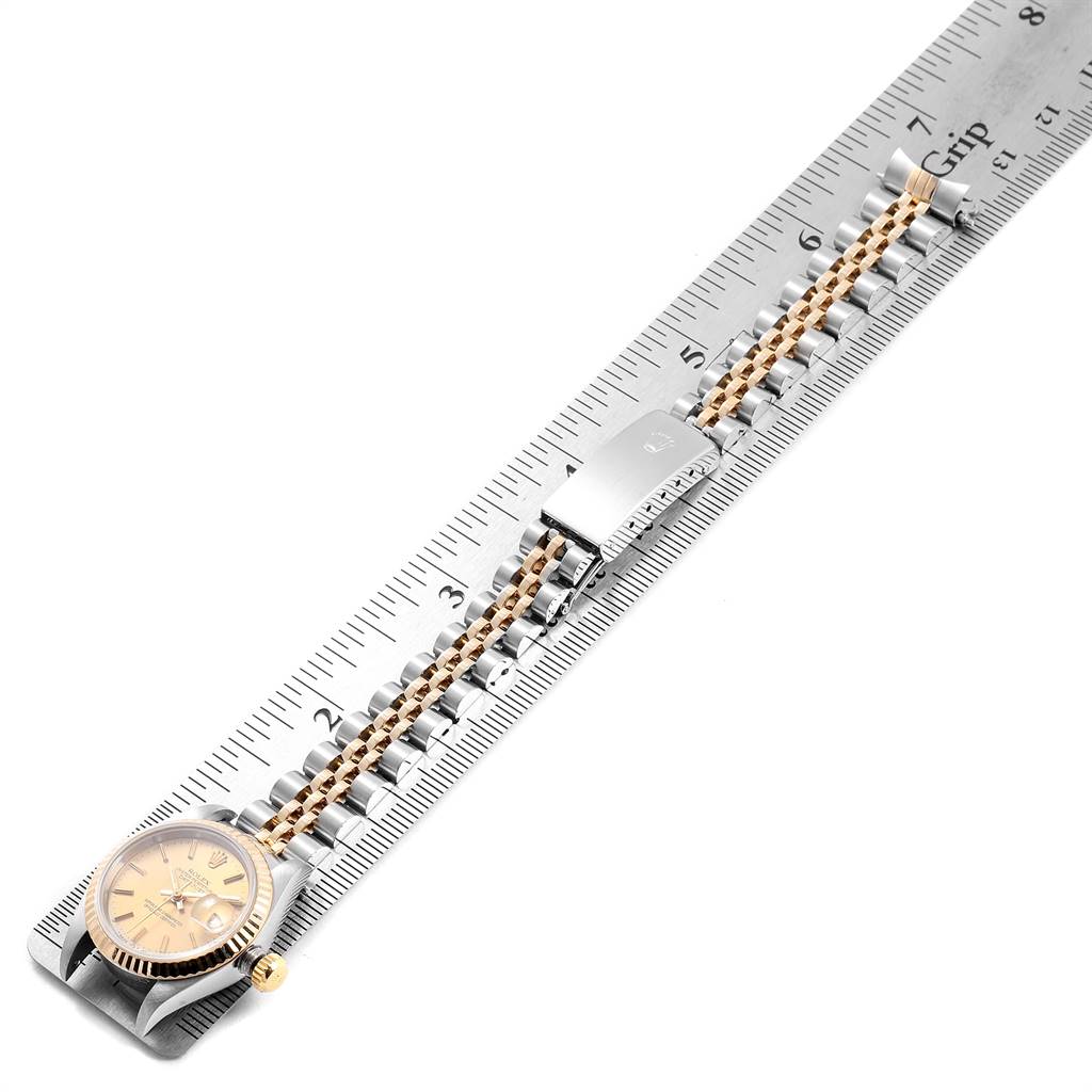 The image shows the Rolex Datejust 69173 Women's Steel and Gold (two tone) Champagne Dial 69173 Women's Steel and Gold (two tone) Champagne Dial watch laid flat on a ruler, displaying the face, band, and clasp.
