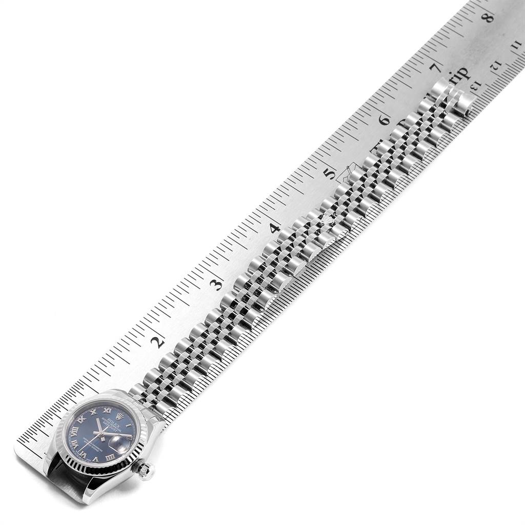 The image shows a Rolex Datejust 179174 Women's Stainless Steel Blue Dial 179174 Women's Stainless Steel Blue Dial watch placed next to a ruler, highlighting its strap and bezel from a top-down angle.