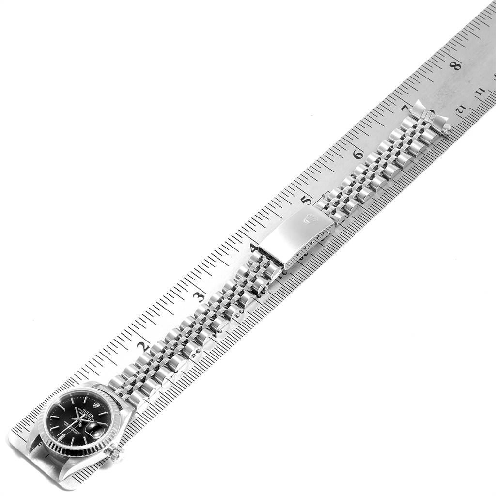 The image shows a Rolex Datejust 79174 Women's Stainless Steel Black Dial 79174 Women's Stainless Steel Black Dial watch placed diagonally on a ruler, displaying the watch face and full bracelet.