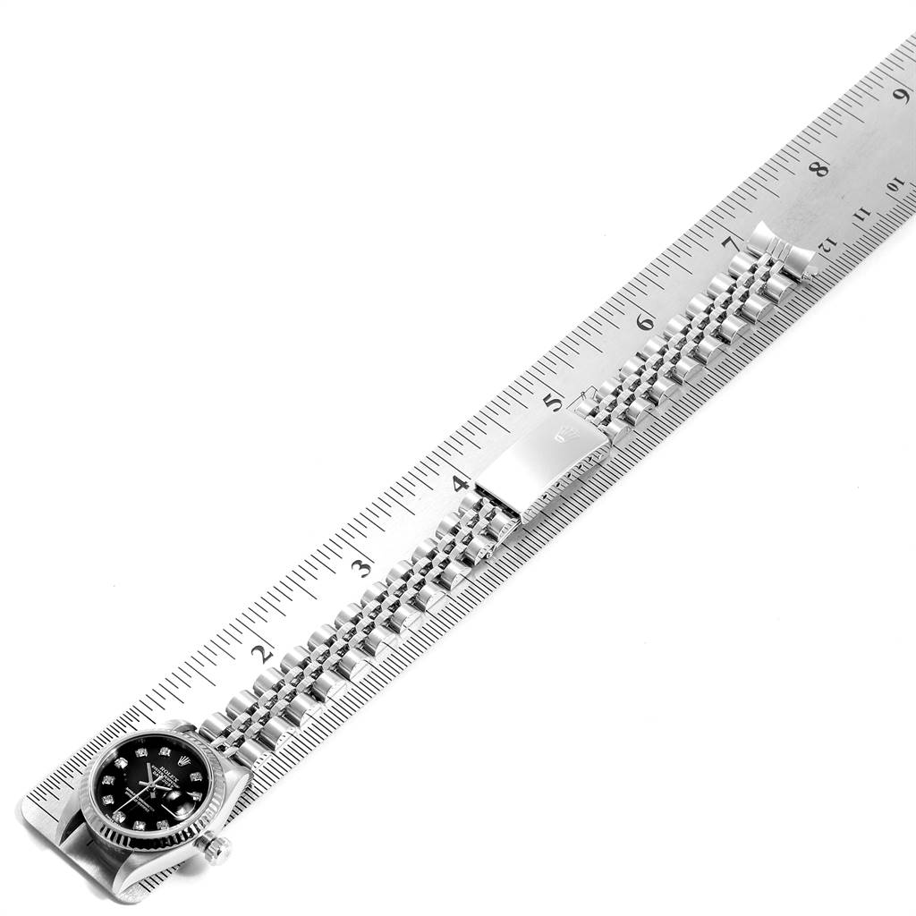 The image shows a Rolex Datejust 79174 Women
s Stainless Steel Black Dial 79174 Women
s Stainless Steel Black Dial watch laid flat against a ruler, highlighting the watch band and part of the face.