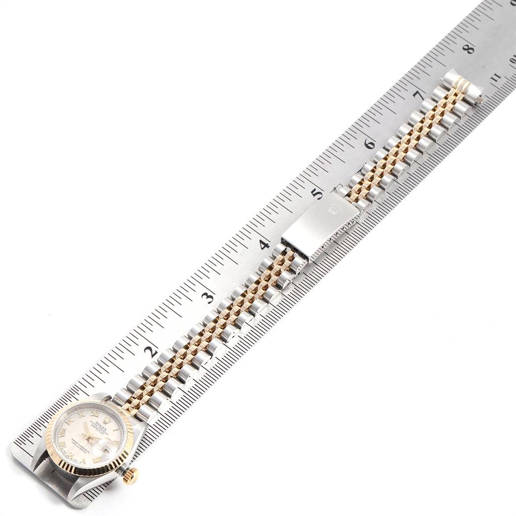 The image shows a flat view of a Rolex Datejust 69173 Women
s Stainless Steel Beige Dial 69173 Women
s Stainless Steel Beige Dial watch with its band extended and measured against a metal ruler.