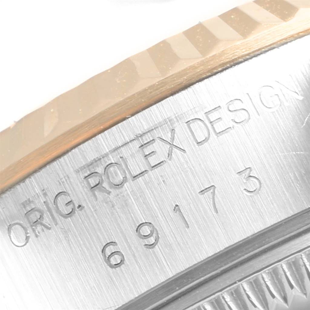 The image shows a close-up of the bezel and case side engraved with "ORIG. ROLEX DESIGN" and the serial number of a Rolex Datejust 69173 Women's Stainless Steel White Dial 69173 Women's Stainless Steel White Dial.