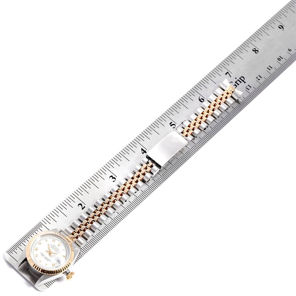 The Rolex Datejust 69173 Women's Stainless Steel White Dial 69173 Women's Stainless Steel White Dial watch is shown from above, displaying its gold and silver bracelet and part of the dial, placed on a ruler.