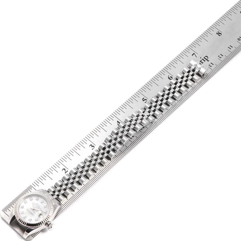 This image shows a Rolex Datejust 179174 Women
s Stainless Steel Mother of Pearl Dial 179174 Women
s Stainless Steel Mother of Pearl Dial watch placed next to a ruler, displaying the face and full length of the bracelet from an overhead angle.