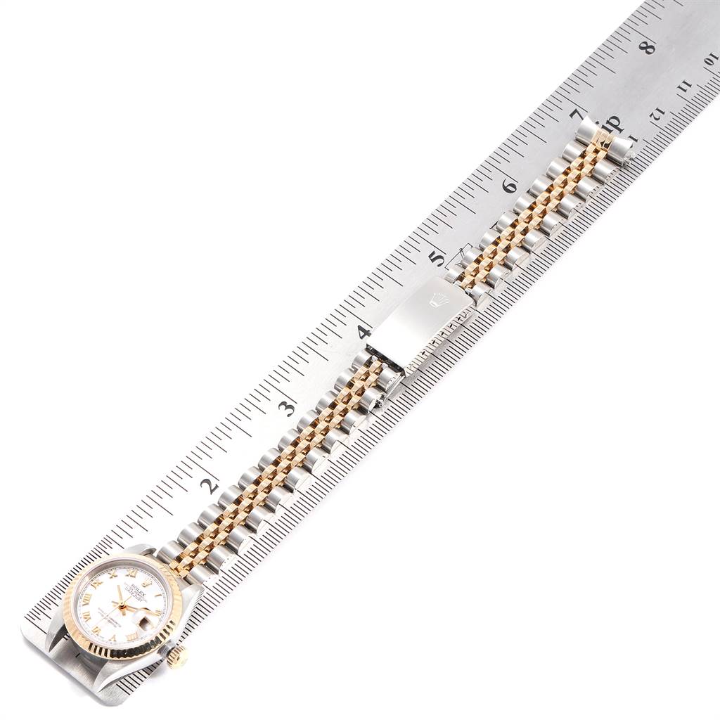 The Rolex Datejust 79173 Women's Steel and Gold (two tone) Mother of Pearl Dial 79173 Women's Steel and Gold (two tone) Mother of Pearl Dial watch is shown from the top angle with its face, bracelet, and clasp on a ruler for measurement.