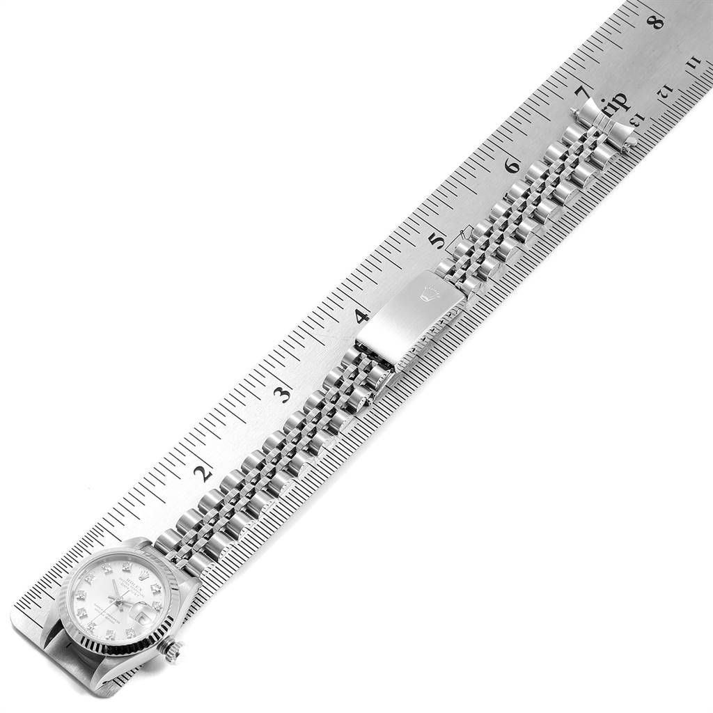 The image shows a Rolex Datejust 69174 Women
s Stainless Steel Silver Dial 69174 Women
s Stainless Steel Silver Dial watch positioned next to a ruler, displaying its face, case, and full bracelet.