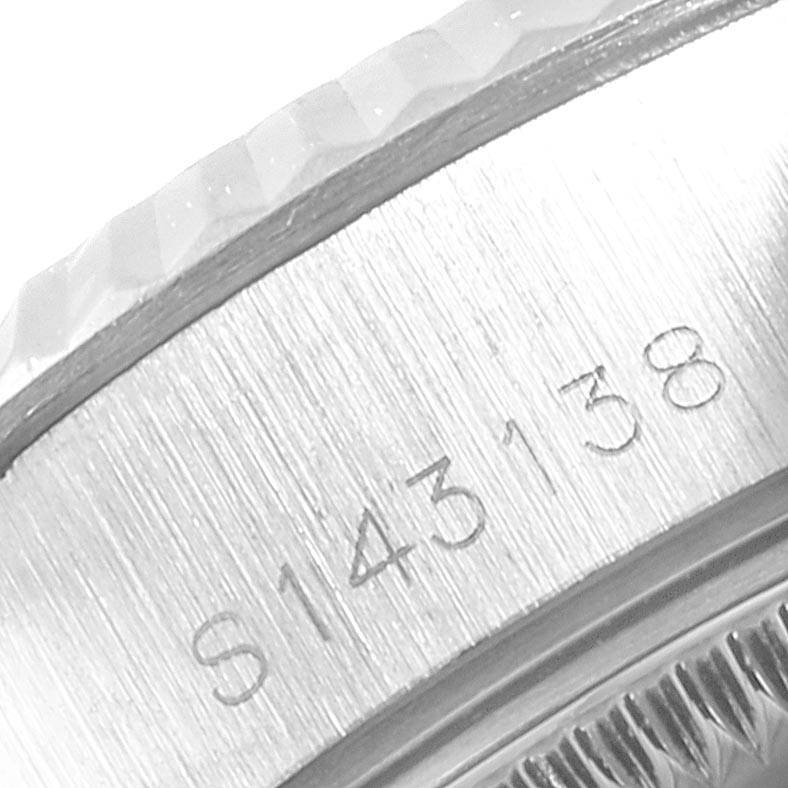 The image shows a close-up of the Rolex Datejust 69174 Women
s Stainless Steel Silver Dial 69174 Women
s Stainless Steel Silver Dial model
s bezel and engraved serial number.
