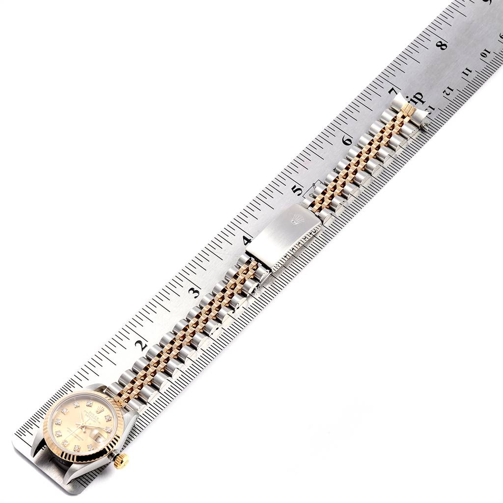 The Rolex Datejust 69173 Women's Stainless Steel Champagne Dial 69173 Women's Stainless Steel Champagne Dial watch is shown with a full view, laying flat on a ruler, displaying the face and band.