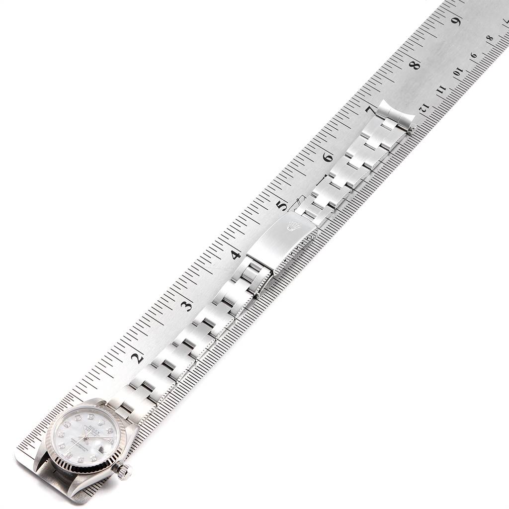 The image shows a Rolex Datejust 79174 Women
s Stainless Steel Mother of Pearl Dial 79174 Women
s Stainless Steel Mother of Pearl Dial watch laid flat on a ruler, displaying its face and metal bracelet from above.