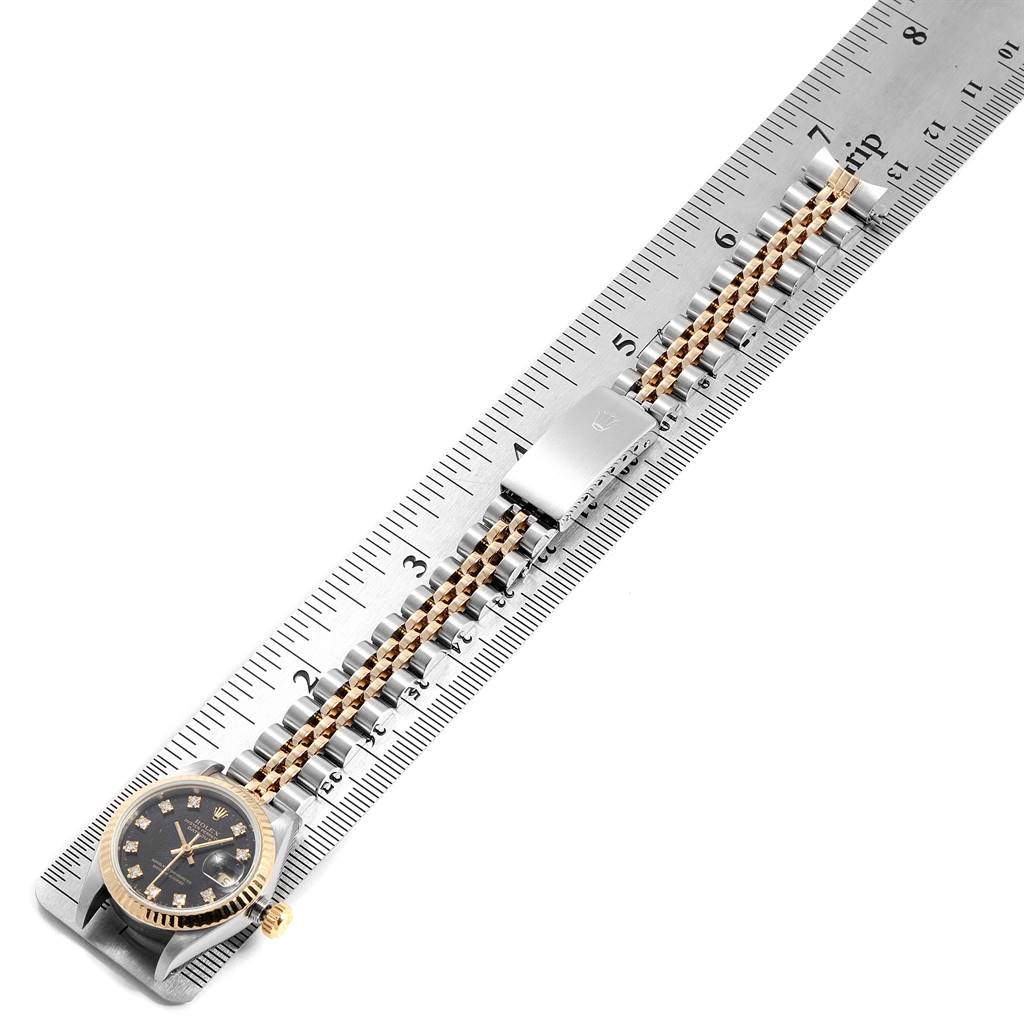The image shows a Rolex Datejust 79173 Women's Stainless Steel Black Dial 79173 Women's Stainless Steel Black Dial watch laid flat on a ruler, highlighting its bracelet, clasp, and face.