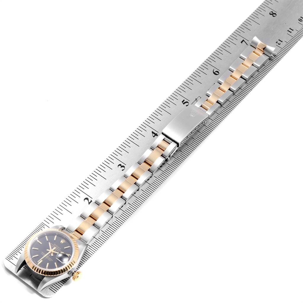 The image shows a Rolex Datejust 69173 Women's Steel and Gold (two tone) Black Dial 69173 Women's Steel and Gold (two tone) Black Dial watch from a top-down angle, displaying the face, bezel, and bracelet alongside a ruler for measurement.