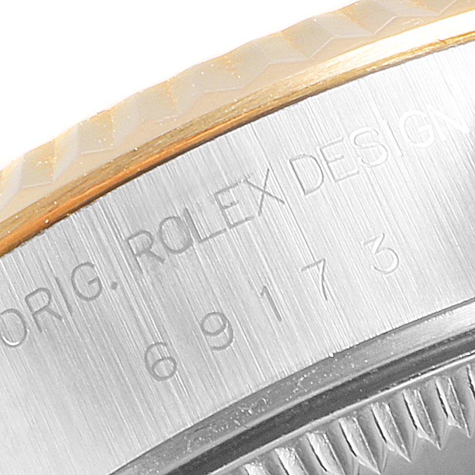 This image shows a close-up of the engraved inscription and the fluted bezel part of a Rolex Datejust 69173 Women's Steel and Gold (two tone) Black Dial 69173 Women's Steel and Gold (two tone) Black Dial watch.