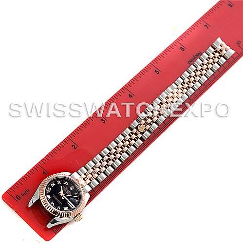 This image shows a Rolex Datejust 179171 Women's Steel and Gold (two tone) Black Dial 179171 Women's Steel and Gold (two tone) Black Dial watch laid flat on a ruler, highlighting its face and full bracelet.