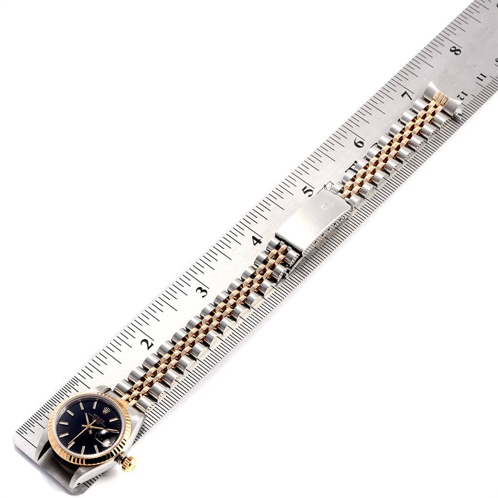 The Datejust model by Rolex is shown from above, highlighting its bracelet and clasp against a ruler for size reference.