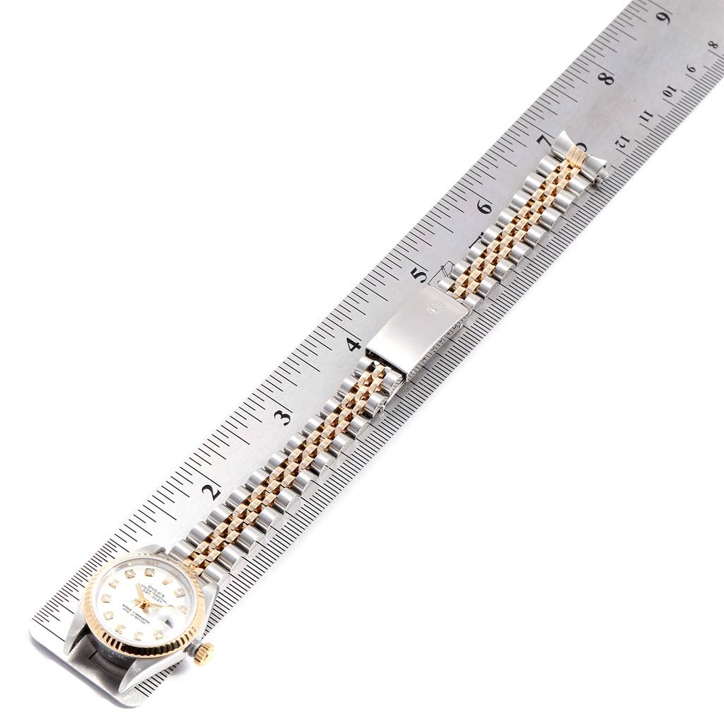 The Rolex Datejust 79173 Women's Stainless Steel White Dial 79173 Women's Stainless Steel White Dial watch is shown lying flat on a ruler, displaying its face, bracelet, and clasp.