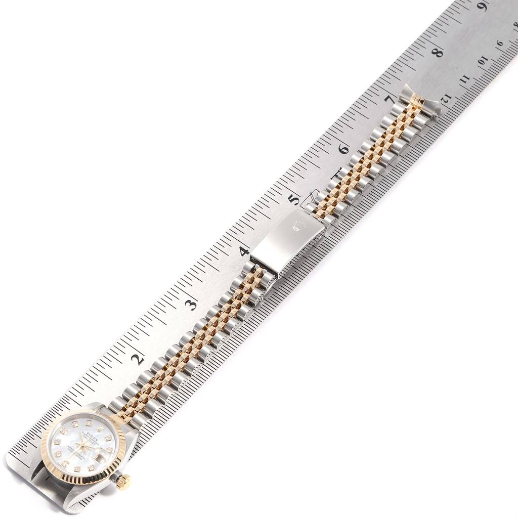 This image shows a Rolex Datejust 79173 Women's Stainless Steel Mother of Pearl Dial 79173 Women's Stainless Steel Mother of Pearl Dial watch laid flat next to a ruler, displaying the face, bracelet, and clasp.