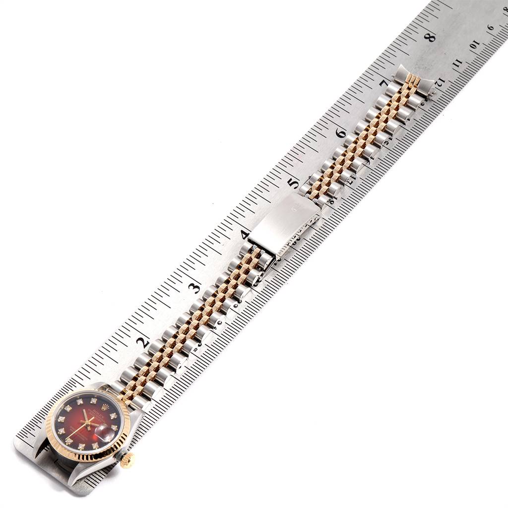 The Rolex Datejust 69173 Women's Stainless Steel Red Dial 69173 Women's Stainless Steel Red Dial watch is displayed alongside a ruler showing the face, bracelet, and clasp laid flat.