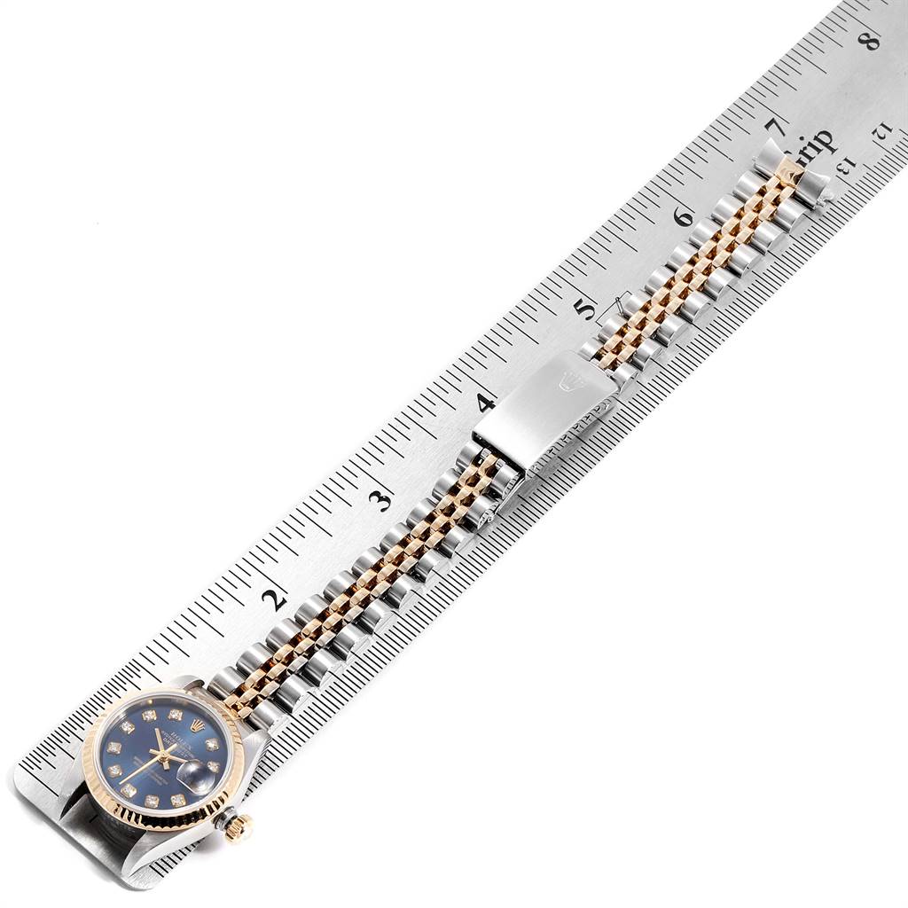 This image shows a Rolex Datejust 79173 Women
s Stainless Steel Blue Dial 79173 Women
s Stainless Steel Blue Dial watch laid flat with its band extended beside a ruler, displaying the watch face and bracelet.