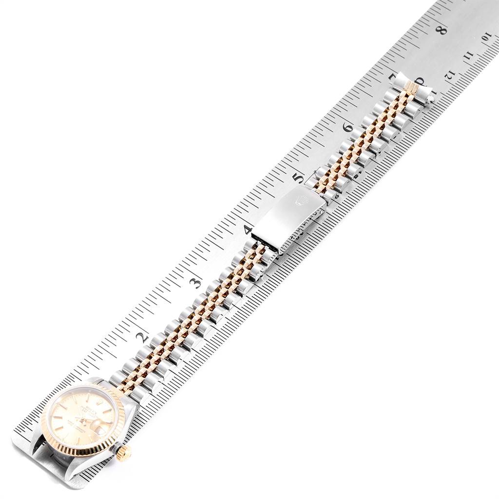 The image shows a top view of a Rolex Datejust 69173 Women's Stainless Steel Champagne Dial 69173 Women's Stainless Steel Champagne Dial watch with its face, band, and clasp alongside a ruler.