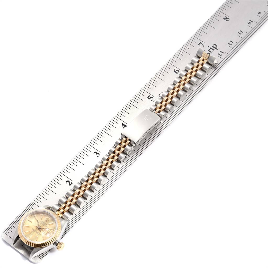 The Rolex Datejust 69173 Women
s Stainless Steel Champagne Dial 69173 Women
s Stainless Steel Champagne Dial watch is shown from a top view, highlighting the dial, bracelet, and clasp alongside a measuring ruler.