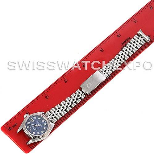 The image shows a Rolex Datejust 79174 Women's Stainless Steel Blue Dial 79174 Women's Stainless Steel Blue Dial watch laid flat against a red ruler, displaying the bracelet and watch face.