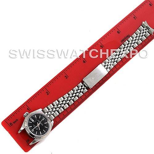 The Rolex Datejust 69174 Women's Stainless Steel Black Dial 69174 Women's Stainless Steel Black Dial watch is shown from the top, displaying its dial, bezel, and bracelet alongside a red ruler for scale.