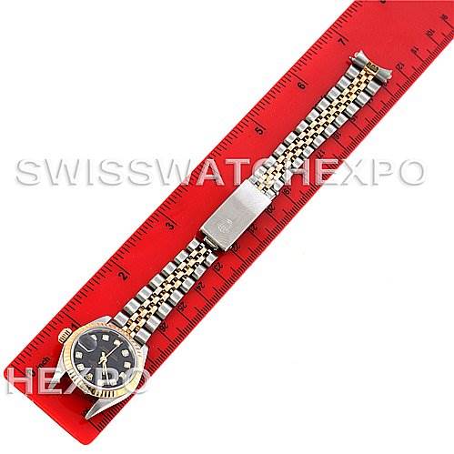 This image shows a Rolex Datejust 79173 Women's Stainless Steel Black Dial 79173 Women's Stainless Steel Black Dial watch placed alongside a red ruler, displaying the watch face and full bracelet.