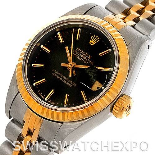 The image shows a close-up of the Rolex Datejust 69173 Women's Stainless Steel Black Dial 69173 Women's Stainless Steel Black Dial watch, highlighting its black dial, gold fluted bezel, crown, and two-tone bracelet.