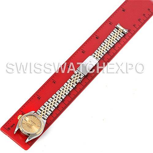 This is a top-down view of a Rolex Datejust 79173 Women's Stainless Steel Champagne Dial 79173 Women's Stainless Steel Champagne Dial watch placed alongside a red ruler, displaying the face, bezel, and bracelet.
