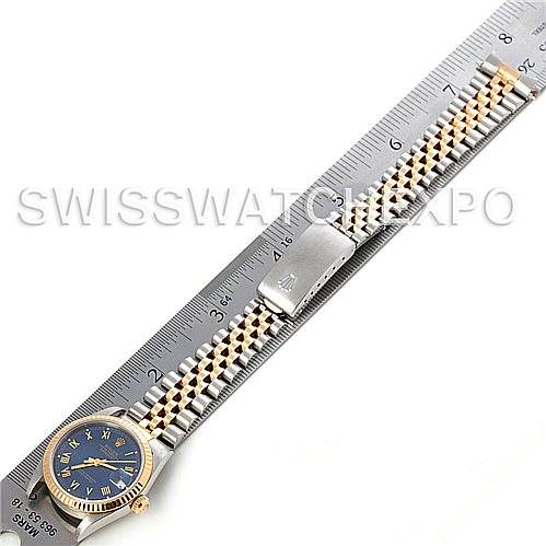 The image shows the top view of a Mid-Size Rolex watch, including its face, bracelet, and clasp, beside a ruler for scale.