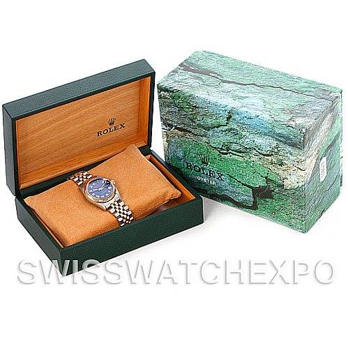 The image shows a Rolex Mid-Size 68273 Women's Stainless Steel Blue Dial 68273 Women's Stainless Steel Blue Dial watch in an open green box with a pillow, alongside a closed outer box with a green marbled pattern.