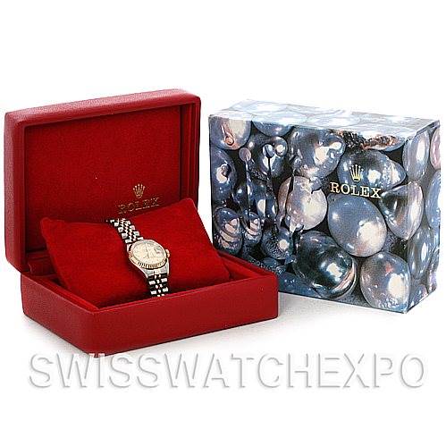 This image shows a Rolex Datejust 79173 Women's Stainless Steel Champagne Dial 79173 Women's Stainless Steel Champagne Dial watch in a red box, next to an artistic Rolex-branded outer box.