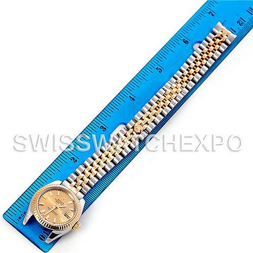 The image shows a Rolex Datejust 179173 Women's Steel and Gold (two tone) Champagne Dial 179173 Women's Steel and Gold (two tone) Champagne Dial watch laying flat with its gold and silver bracelet aligned along a blue ruler for scale.