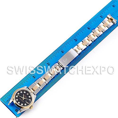 The Rolex Datejust 79163 Women's Steel and Gold (two tone) Black Dial 79163 Women's Steel and Gold (two tone) Black Dial watch is shown from a top-down angle, displaying its full bracelet and face next to a blue ruler for size reference.