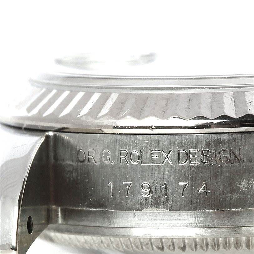 This close-up shows the side of the Rolex Datejust 179174 Women's Stainless Steel Blue Dial 179174 Women's Stainless Steel Blue Dial watch case, featuring the fluted bezel and engraved serial number.