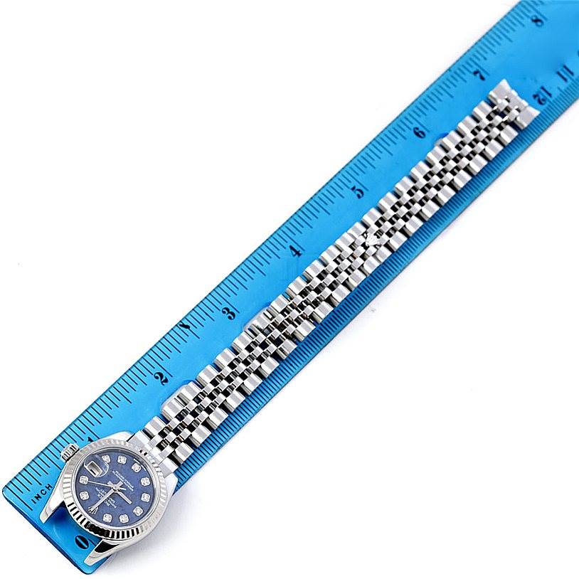 The Rolex Datejust 179174 Women's Stainless Steel Blue Dial 179174 Women's Stainless Steel Blue Dial watch is shown from a top-down angle, displaying the face, bezel, and full stainless steel bracelet against a ruler.