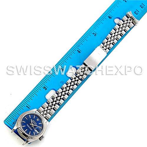 This image shows a Rolex Datejust 79174 Women's Stainless Steel Blue Dial 79174 Women's Stainless Steel Blue Dial watch laid flat next to a blue ruler, displaying the entire watch and bracelet.