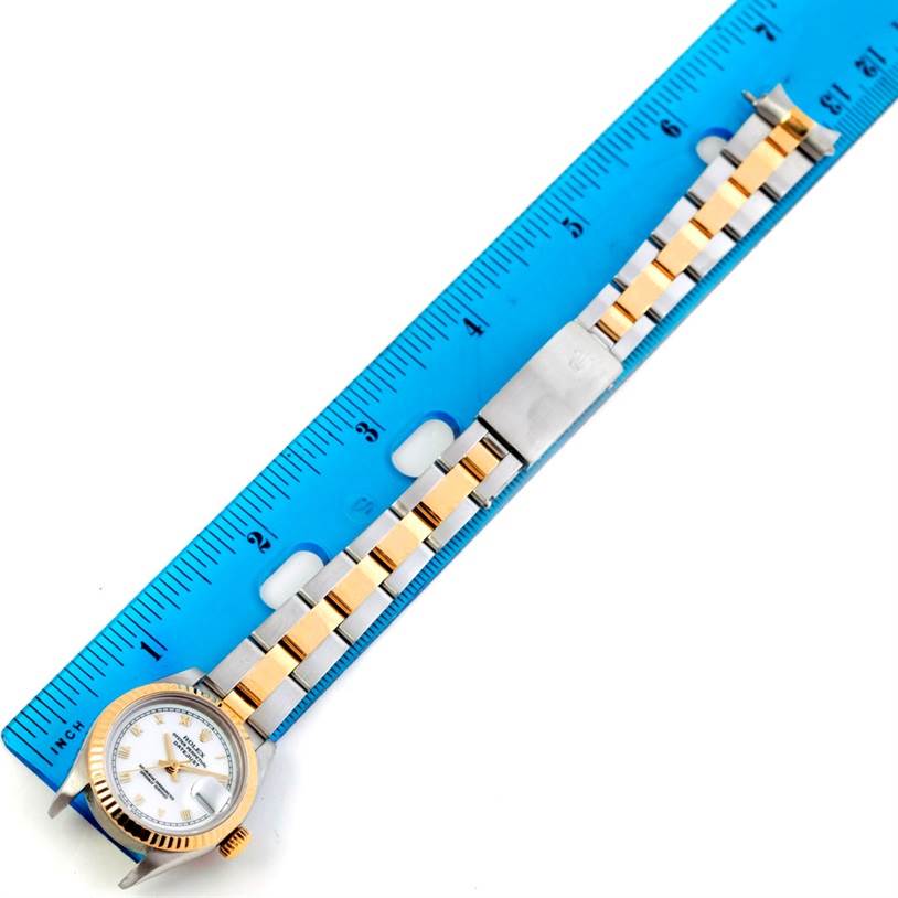 The image shows a Rolex Datejust 69173 Women's Stainless Steel White Dial 69173 Women's Stainless Steel White Dial watch lying flat next to a blue ruler, displaying its gold and silver metal bracelet.