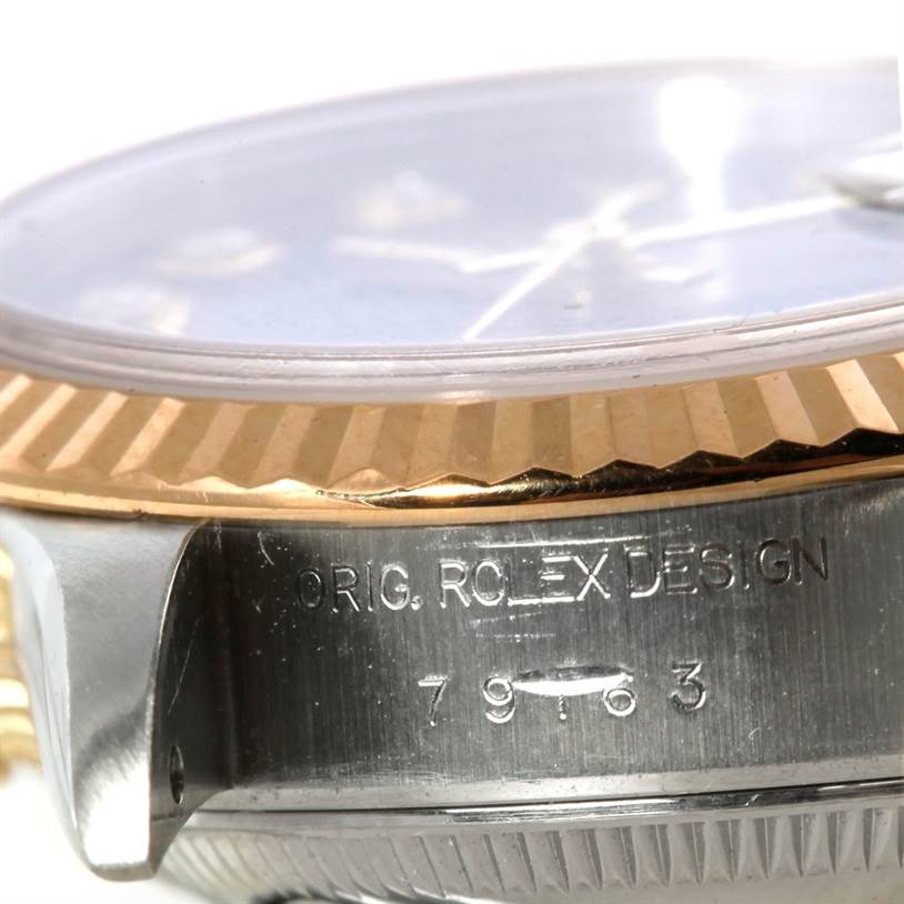 This image shows a close-up of the Rolex Datejust 79163 Women's Steel and Gold (two tone) Black Dial 79163 Women's Steel and Gold (two tone) Black Dial case with "ORIG. ROLEX DESIGN" and the reference number engraved.