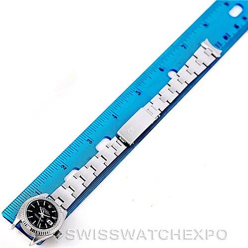 The image shows a Rolex Datejust 79174 Women's Stainless Steel Black Dial 79174 Women's Stainless Steel Black Dial watch laid flat next to a blue ruler, displaying the band and the watch face.