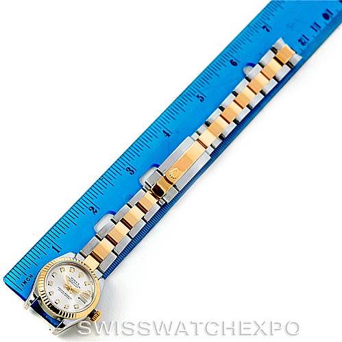 The image shows a Rolex Datejust 179173 Women's Steel and Gold (two tone) Silver Dial 179173 Women's Steel and Gold (two tone) Silver Dial watch laid flat with a blue ruler beside it, displaying the face, bracelet, and clasp.