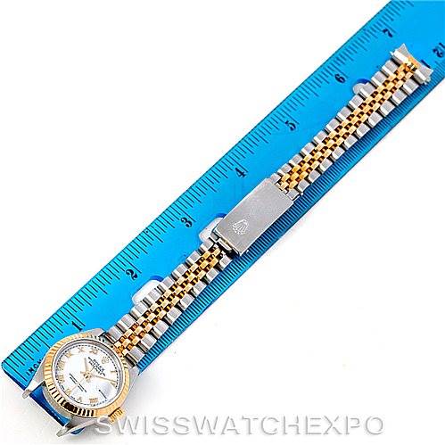 The Rolex Datejust 79173 Women
s Stainless Steel White Dial 79173 Women
s Stainless Steel White Dial watch is shown from a top-down angle with the face, band, and deployment clasp visible next to a blue ruler.