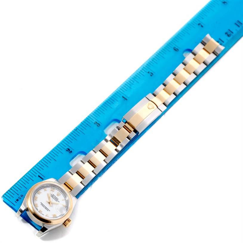 The image shows a top-down view of a Rolex Datejust 179163 Women's Steel and Gold (two tone) White Dial 179163 Women's Steel and Gold (two tone) White Dial model, highlighting its watch face and metal bracelet placed on a ruler.