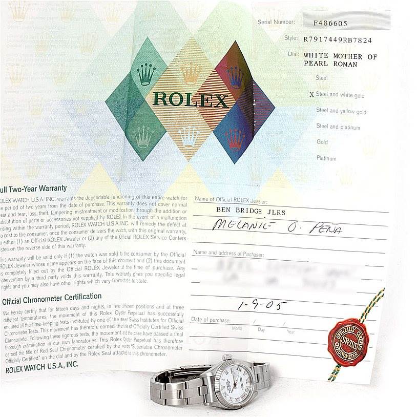 The image shows the Rolex Datejust 79174 Women's Stainless Steel Mother of Pearl Dial 79174 Women's Stainless Steel Mother of Pearl Dial watch positioned beside its warranty card and paperwork, viewed from a front angle.